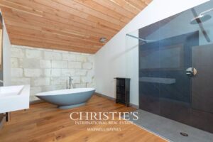 Une salle de bain moderne avec une baignoire ovale, un parquet en bois, un mur de pierre, et une douche à l'italienne avec paroi vitrée.