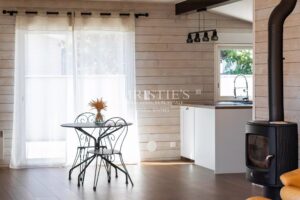 Une salle à manger lumineuse avec une table ronde et des chaises en métal noir, près d'un poêle à bois, dans un intérieur de style scandinave.
