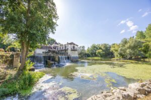 La maison du moulin, située au bord de la rivière Dropt, surplombe son lac et s’étend au cœur d’un domaine boisé de 13 hectares